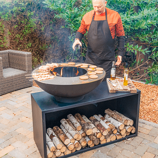 Koken op een vuurschaal met plancha en houtopslag