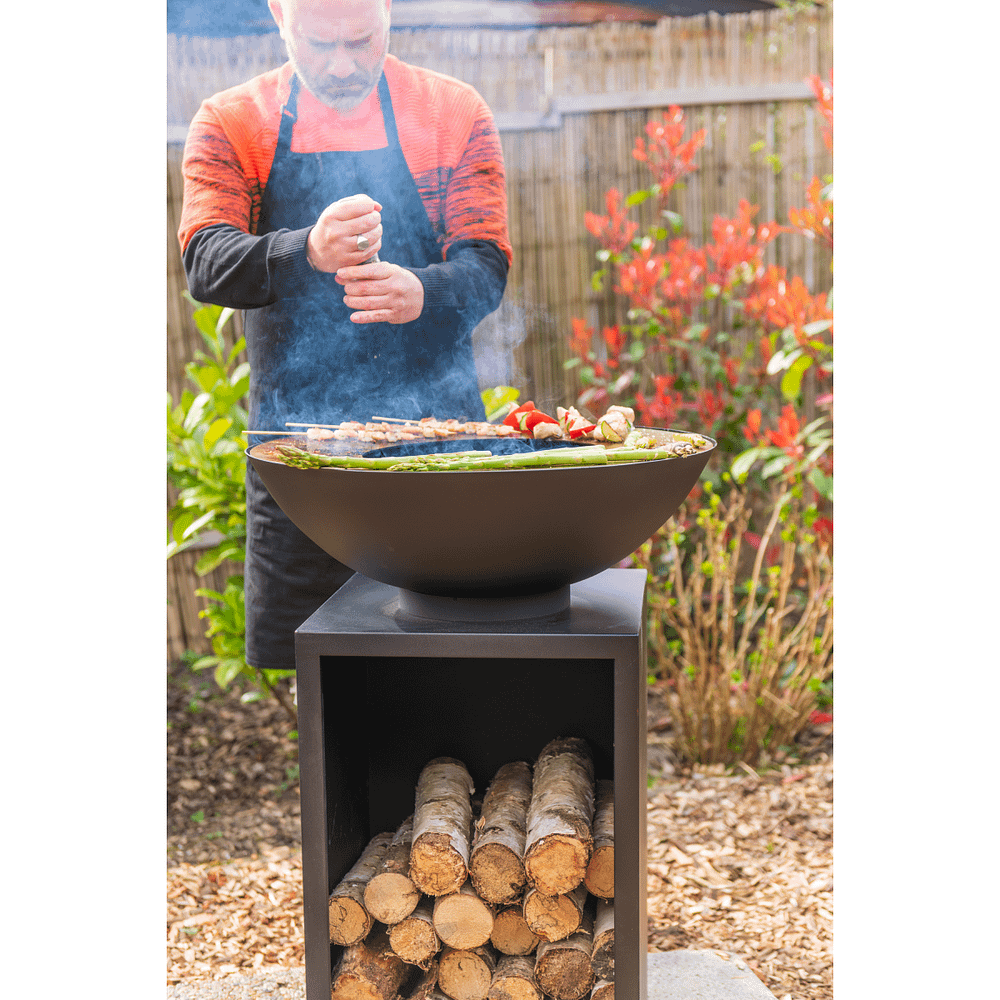 Sfeerfoto koken met een vuurschaal plancha met houtopslag